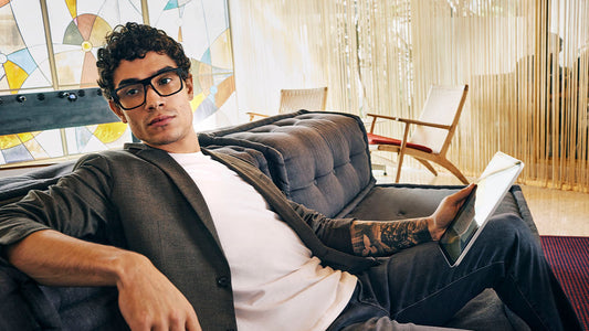 Man wearing blue light glasses sitting on a couch